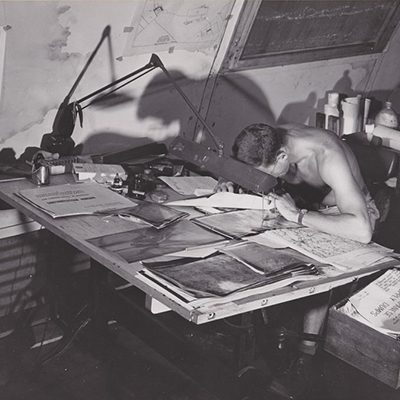 US Airman researching aerial photographs and maps. Source: October 1945; U.S. Army Strategic Air Force, Public Relations Photo Lab (Liaison); National Archives and Records Administration. 