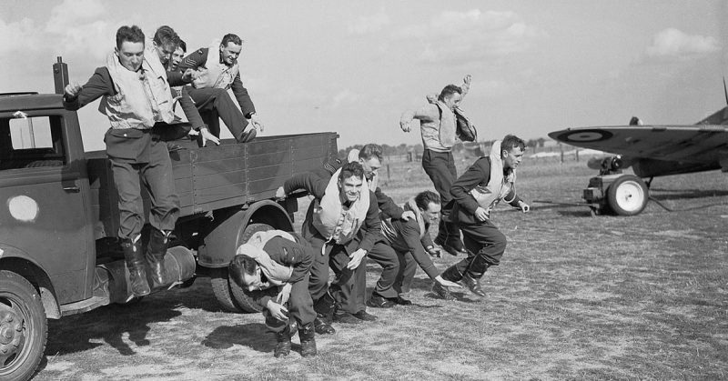 Pilots of No 19 Squadron, Royal Air Force 'scramble' for the photographer, from the back of a lorry at Fowlmere, Cambridgeshire.