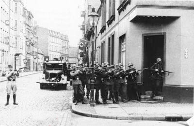 The SS Heimwehr-Danzig huddle around a doorway keeping the Poczta Polska under close observation