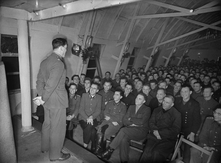 British officer addresses German Prisoners of War in their recreation hut at a PoW camp, somewhere in Britain.