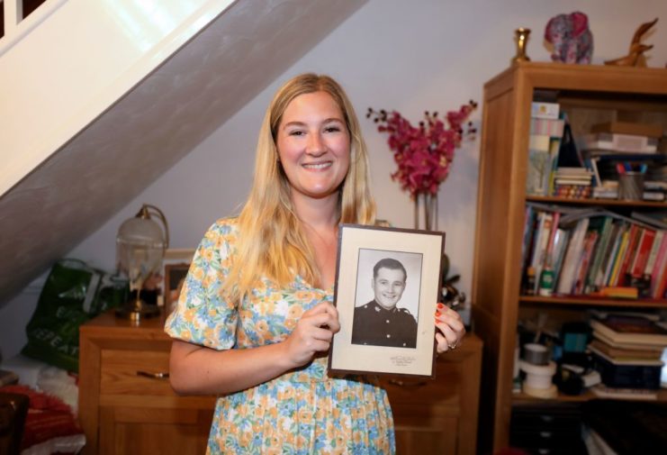 Female relative of Dennis Morley holding up his military portrait