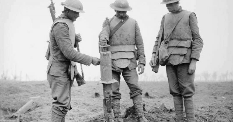 Three Irish Guardsmen wearing German body-armour, examining a captured German machine-gun.