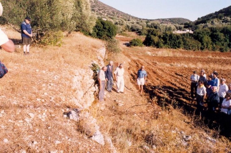 Veterans of Cephalonia in recollection where their comrades were machine-gunned and then burned. The bodies were then thrown into the spring wells because the flames did not erase the crime committed