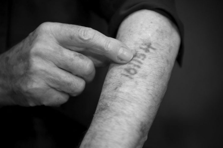 A survivor showing his number he got in Auschwitz.