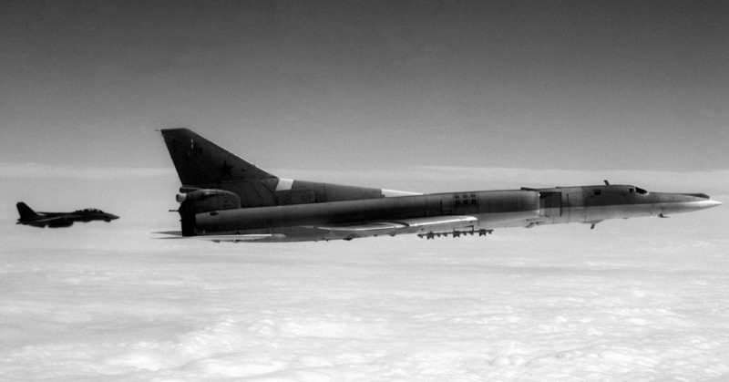 Soviet Tu-22M Backfire-B bomber aircraft is escorted by an F-14A Tomcat aircraft.
