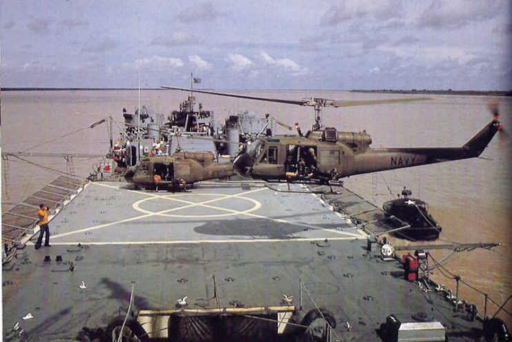 A Bell UH-1E Huey helicopter of U.S. Navy light helicopter attack squadron HAL-3 Seawolves landing on the converted tank landing ship USS Harnett County (LST-821) between combat operations in the Mekong Delta, Co Chien river, South Vietnam, in October 1967. A U.S. Army UH-1B is parked in the background.