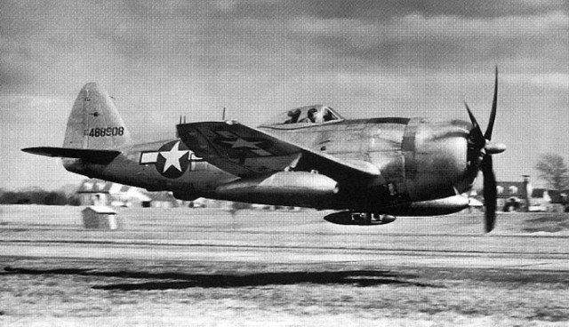 A USAAF P-47 Thunderbolt at extreme low level. Note that the sweep of the camera’s pan has bent the buildings in the background.