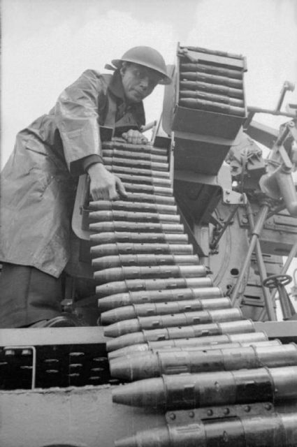 Ammunition is loaded into the racks of a 2 pounder multiple pom-pom gun on board an anti-aircraft ship, somewhere in England, 1940.