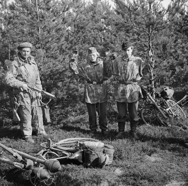 A soldier from 11th Armoured Division guards two youthful German prisoners and a haul of ‘Panzerfaust’ anti-tank weapons, 7 April 1945. The Germans were part of a bicycle-mounted tank-hunting unit.