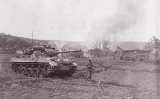 Hellcat with walking GI in front of a burning town. This photo was identified by its driver Sgt. Harry E. Traynor of the 704th TD Bn. The soldier in the front is Cpt. Marion Taake, The TD was named “Blondie” and it was later destroyed on February 9, 1945 by two German Panther tanks in the Bannholz Woods area of Germany