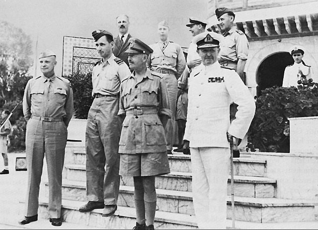 Allied leaders in the Sicilian campaign. General Dwight D. Eisenhower meets in North Africa with (foreground, left to right): Air Chief Marshal Sir Arthur Tedder, General Sir Harold Alexander, Admiral Sir Andrew Cunningham, and (top row): Mr. Harold Macmillan, Major General Walter Bedell Smith, and unidentified British officers.
