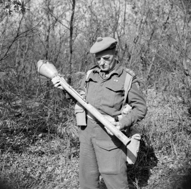 Captain W Guest-Gordons, Intelligence Officer with No. 2 Infantry Brigade, examines a German Panzerfaust anti-tank weapon, Anzio, 27 February 1944.