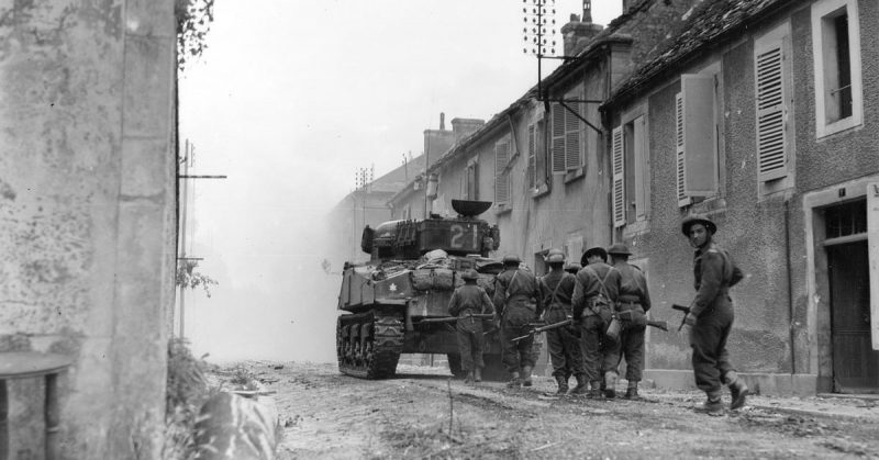 Canadian troops with armour support advance cautiously through the streets of Falaise, encountering only light scattered resistance.