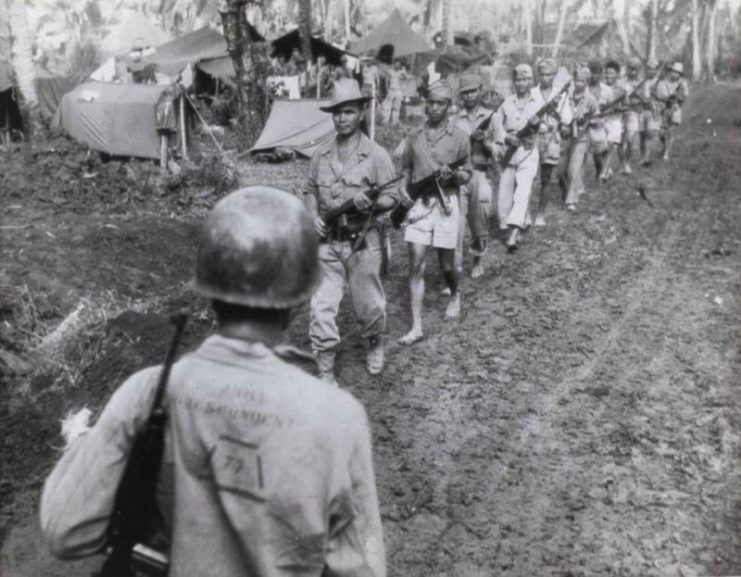 Filipino guerrillas under the command of Captain Jesus Olmedo come out to meet Major General A.V. Arnold at U.S. Army 7th Division headquarters for a conference in 1944.