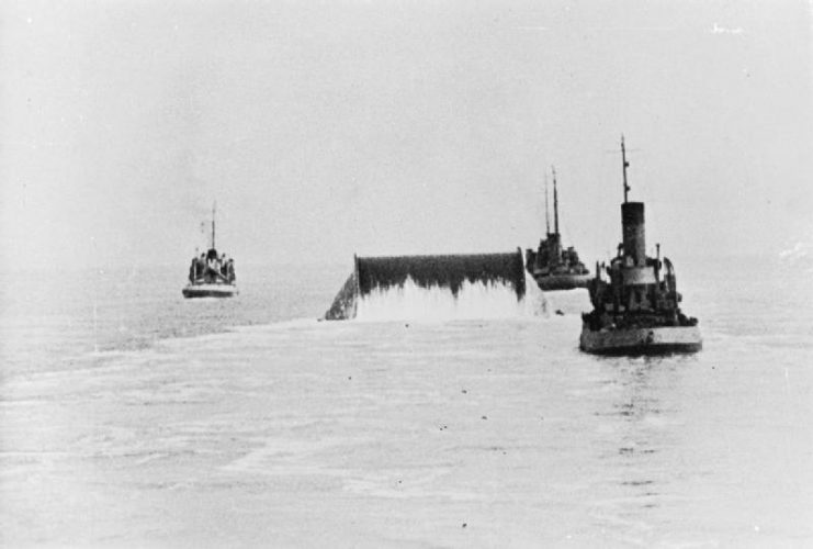 A ConunDrum being towed across the English Channel laying out pipe behind it to form an underwater pipeline from Southampton to Cherbourg which kept the Allied armies supplied with petrol until the French channel ports could be re-activated. Known as Pluto, this was an entirely British concept designed by Captain John Hutchings, Royal Navy.