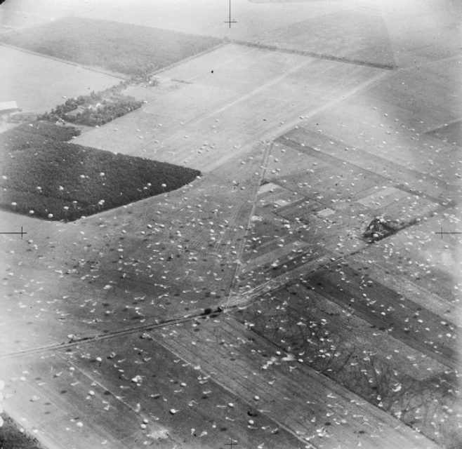 Oblique aerial view from the north showing paratroops of 1st Parachute Brigade, 1st (British) Airborne Division, descending on Dropping Zone (DZ) ‘X’, which is already littered with parachutes left from the previous drop.