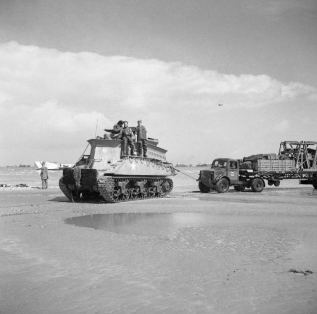 A Sherman BARV tows a disabled Bedford articulated lorry and trailer off the beach, Normandy 1944