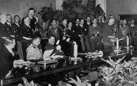 The signing of the Tripartite Pact. On the lefthand side of the picture, seated from left to right, are: Saburō Kurusu (representing Japan), Galeazzo Ciano (Italy) and Adolf Hitler (Germany).