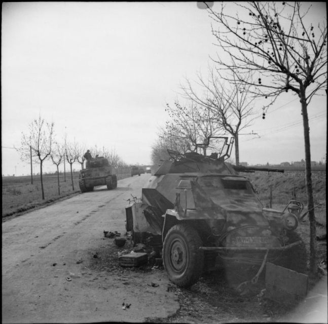 Sherman tanks pass a knocked-out German SdKfz 222 armored car, 25 January 1944.