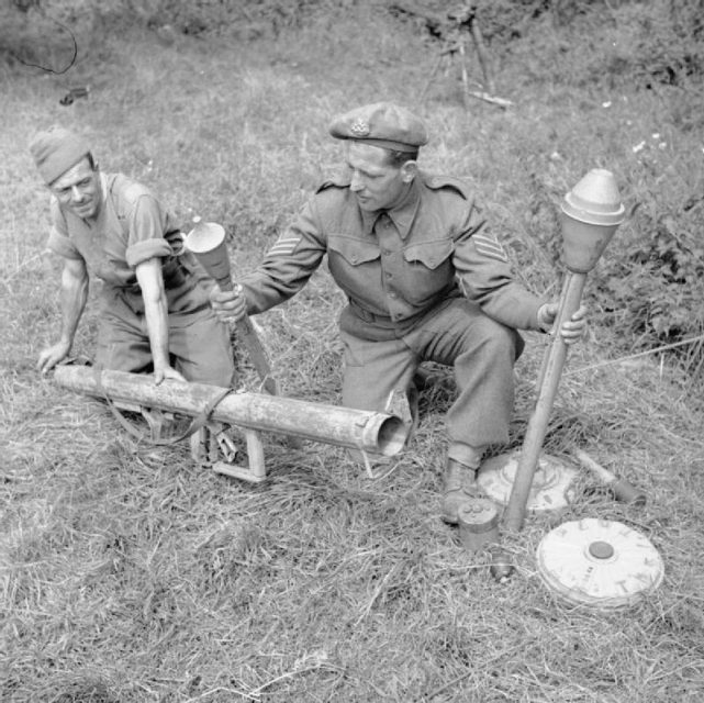 Instructors at a 59th Division school for potential NCOs at Vienne-en-Bessin demonstrate various German anti-tank weapons, including a Panzerschreck, two types of Panzerfaust and anti-tank mines, 1 August 1944.