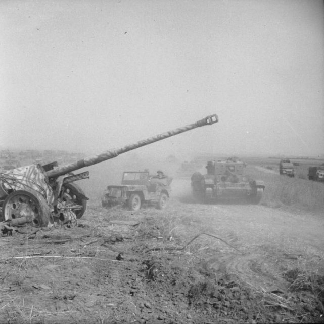 A Cromwell tank and Willys MB jeep passing an abandoned German 88 mm (3.46 in) PaK 43 anti-tank gun during Operation Totalize
