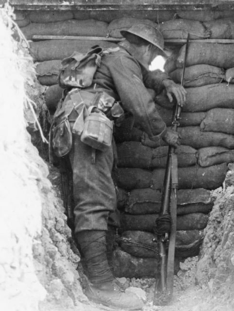 Sentry of the Worcestershire Regiment looking through a loop-hole in a trench, Somme, France.