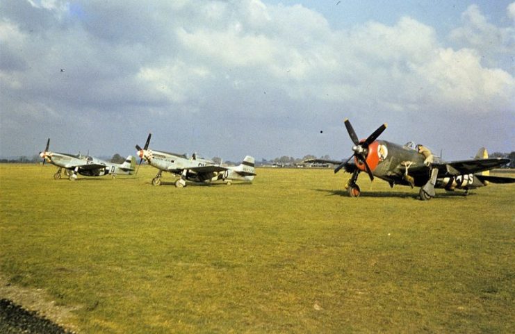 A ground crewman works on a P-47 Thunderbolt beside P-51 Mustangs, (5Q-O, serial number 42-106886) nicknamed “Swede” and (6N-O, serial number 44-14776) nicknamed “Arrow Head”, of the 339th Fighter Group at Mount Farm.