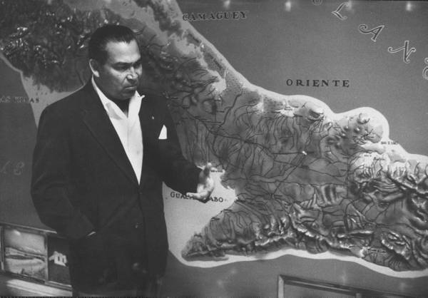 Cuban dictator Fulgencio Batista in March 1957, standing next to a map of the Sierra Maestra mountains where Fidel Castro’s rebels were held up.