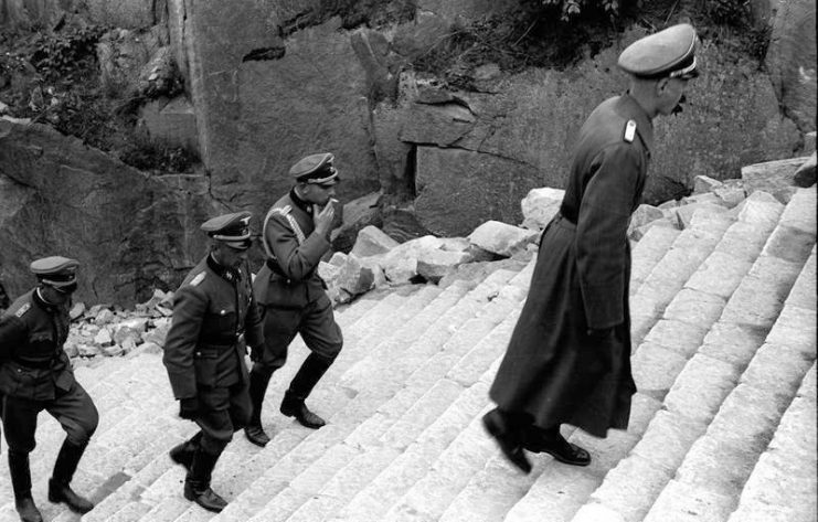 SS officers including General Paul Hausser (far right, in overcoat) climbing the “Stairs of Death”, April 1941.By Bundesarchiv – CC BY-SA 3.0 de