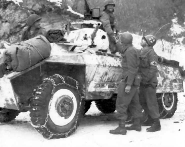 Troops of 84th Division shake hands with an M8 armored car crew from 11th Armored Division after they linked up along the Ourthe River on 16th January 1945.