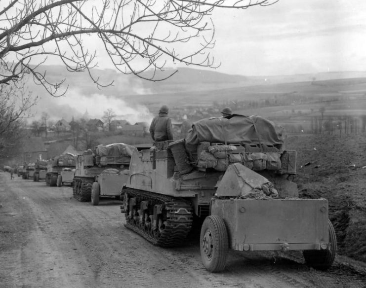 11h Armored Division M7B1 Priest battery rolls into burning Obernust, Germany April 1945