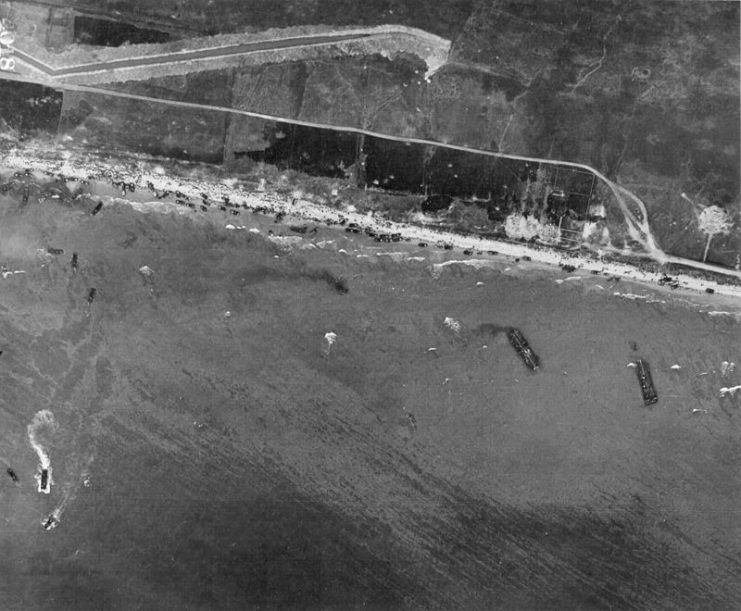 Aerial view of Omaha Beach, Normandy, France, taken 6 June 1944, showing landing of two infantry regiments 18th and 115th, vehicles, and landing craft.