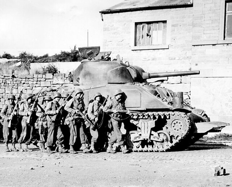 Combined arms in action- US M4 Sherman, equipped with a 75 mm main gun, with infantry walking alongside.