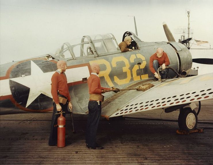 Refueling a U.S. Navy Douglas SBD Dauntless, on the flight deck of a training escort carrier, mid-1943.Hose man, swab man, and fire extinguisher (CO2) man. The plane captain is in the cockpit.