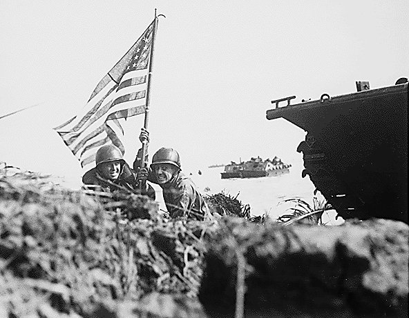 First flag on Guam on boat hook mast. Two U.S. officers plant the American flag on Guam eight minutes after U.S. Marines and Army assault troops landed on the Central Pacific island on July 20, 1944