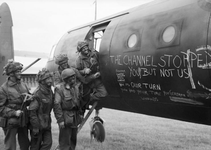 Airborne troops admire the graffiti chalked on the side of their glider as they prepare to fly out as part of the second drop on the night of 6th June 1944.