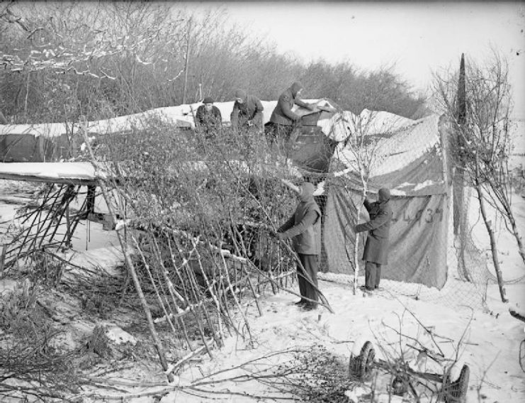 Royal Air Force- France, 1939-1940. Ground crew use a combination of netting and frames of tree branches in an attempt to camouflage Fairey Battle, L4937, of No. 142 Squadron RAF on the snow-bound airfield at Berry-au-Bac