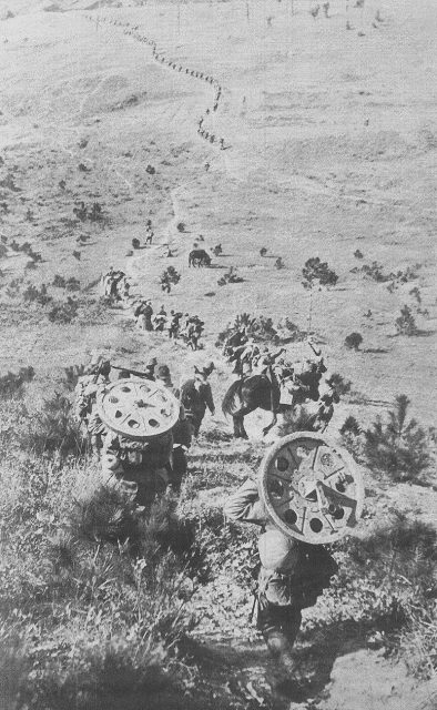 A Japanese military unit gradually approaches Nanking Castle for an assault, carrying guns and wheels on their shoulders and backs. (Dec. 9, 1937)