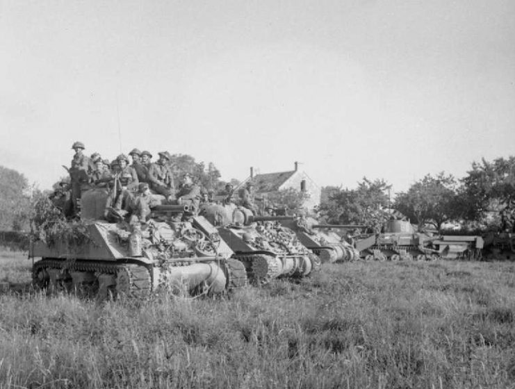 Two M4 Sherman tanks, a Sherman Firefly carrying infantry and a Sherman Crab wait for the order to advance at the start of Operation Goodwood, 18 July