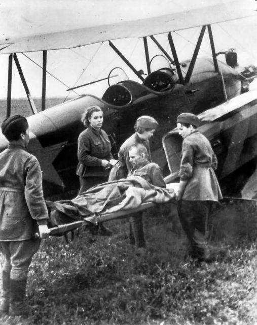 A wounded Russian soldier being loaded onto a U-2 / Po-2 Kukuruznik ambulance plane by nurses