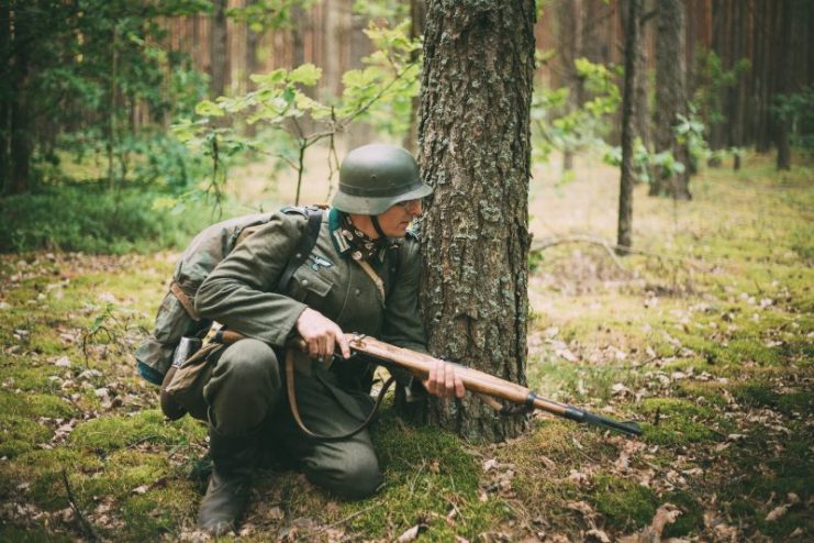 Svetlagorsk, Belarus – June 20, 2014: Unidentified re-enactor dressed as German soldier aiming a rifle in forest during events dedicated to 70th anniversary of Soviet offensive operation ‘Bagration’.