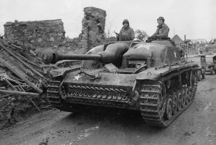 Two soldiers with the 104th Infantry Division riding atop a tank