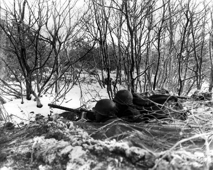 A roadblock is set up with a 30 caliber heavy machine gun, and a tank destroyer is ready for action on Adolf Hitler Strasse, Niederbronn les-Bains, France, by the 1st Battalion, 157th Regiment, 45th Division.