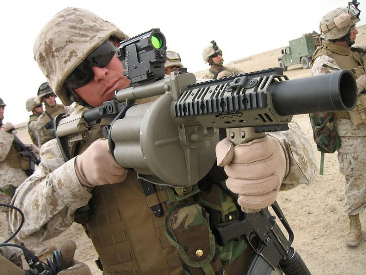 A U.S. Marine holding an American model M-32 6-shot 40 mm launcher, which can be used as a grenade launcher or riot gun depending on the ammunition used.