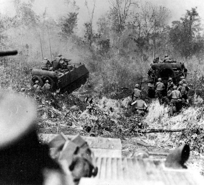 Armored personnel carriers clear the way as infantry follows using vehicles for cover.