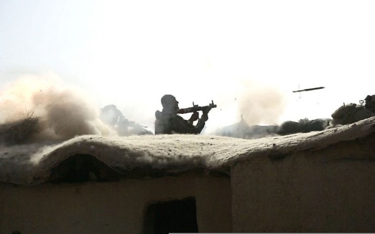 An Afghan National Army commando with the 3rd Company, 3rd Special Operations Kandak fires a rocket-propelled grenade launcher from the roof of a compound