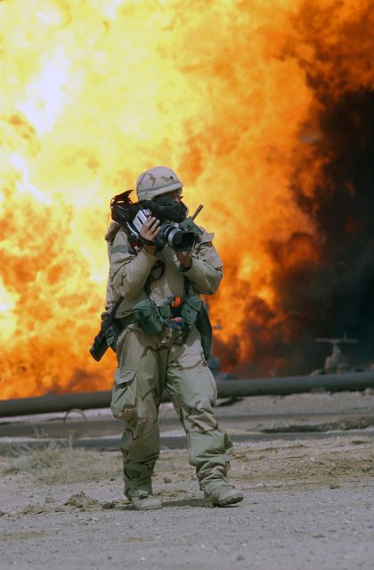 Southern Iraq (Mar. 28, 2003) — Spc. Bernard S. Wiess, a journalist assigned to the 22nd Mobile Public Affairs Detachment gets a close shot with his camera of an oil fire at the Ramaila Oilfield, Iraq