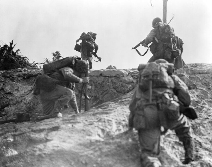 Four US Marines running over a small ridge