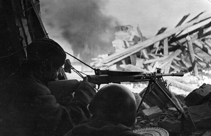 Two Red Army soldiers aiming their machine guns from the interior of a house