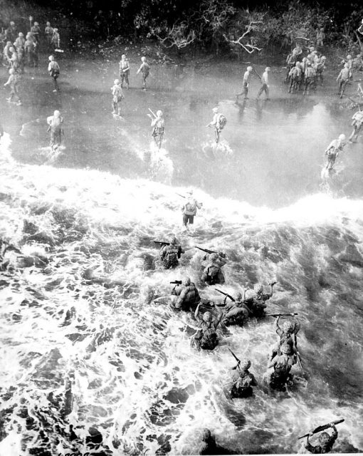 US Marines hit three feet of rough water as they leave their LST to take the beach at Cape Gloucester, New Britain. 26 December 1943.